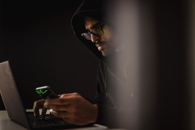 Haker w kapturze przy laptopie